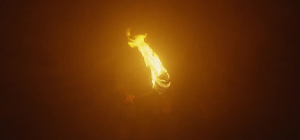 A man with a woman is carrying a torch in the darkness as he looks around
