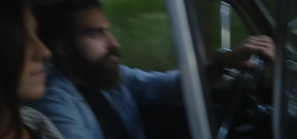 A man and woman drive on a rough forest trail
