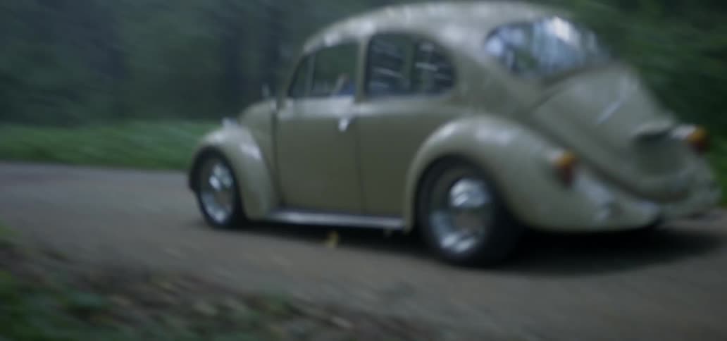 A car is driving on a road in a wooded area