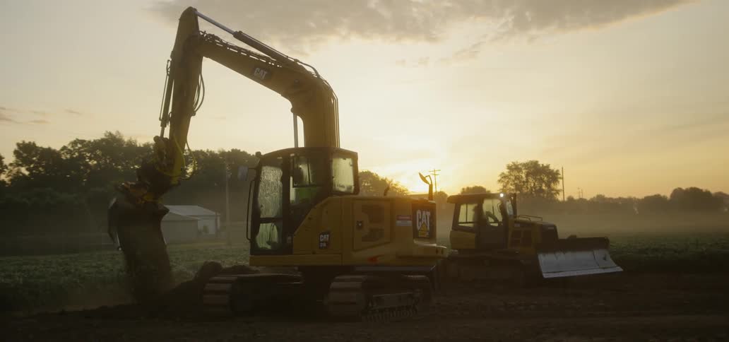 Excavator and Bulldozer moving dirt at sunrise