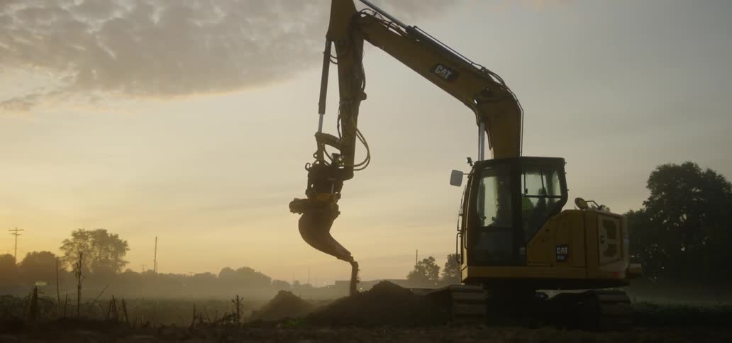 A person is operating a crane and moving dirt