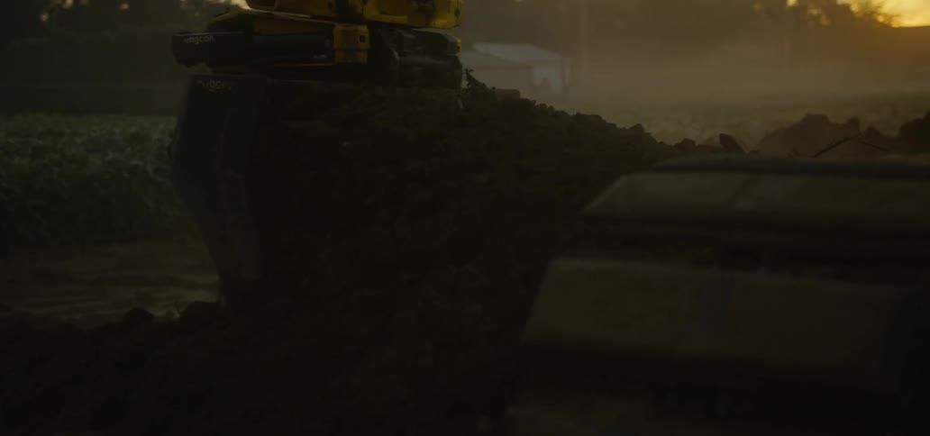 Crane digs up dirt and releases it at sunset