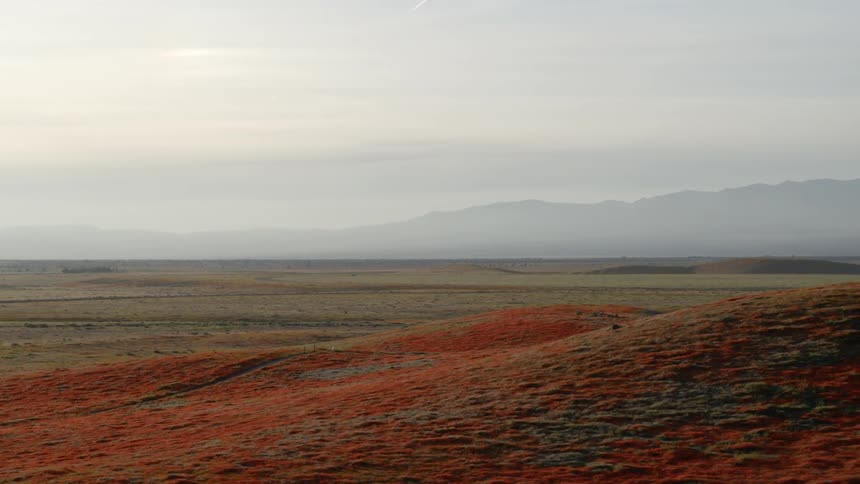 A deserted landscape with misty mountains in the horizon
