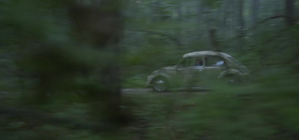A car traveling on a road through the woods