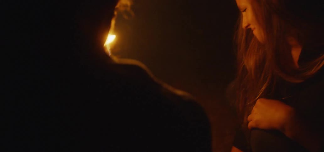 A man uses a flaming torch to illuminate something he shows to a female friend