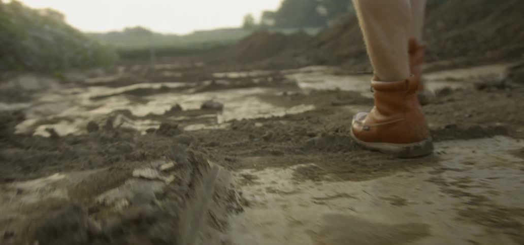 A person in work boots walks on freshly dug ground