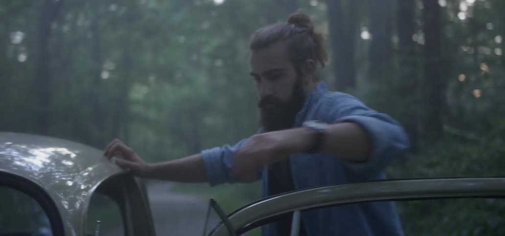 Bearded man stands in the open door of a classic vw beetle