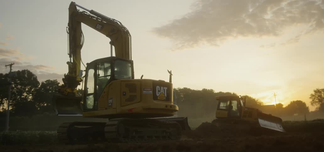 Excavator and Bulldozer moving dirt at sunrise