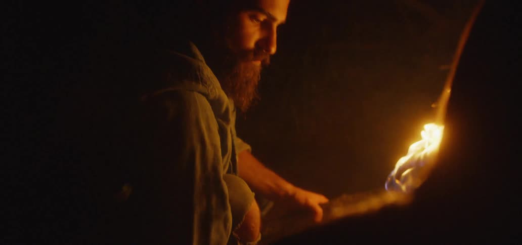 Bearded man holds a torch and looks up at his companion