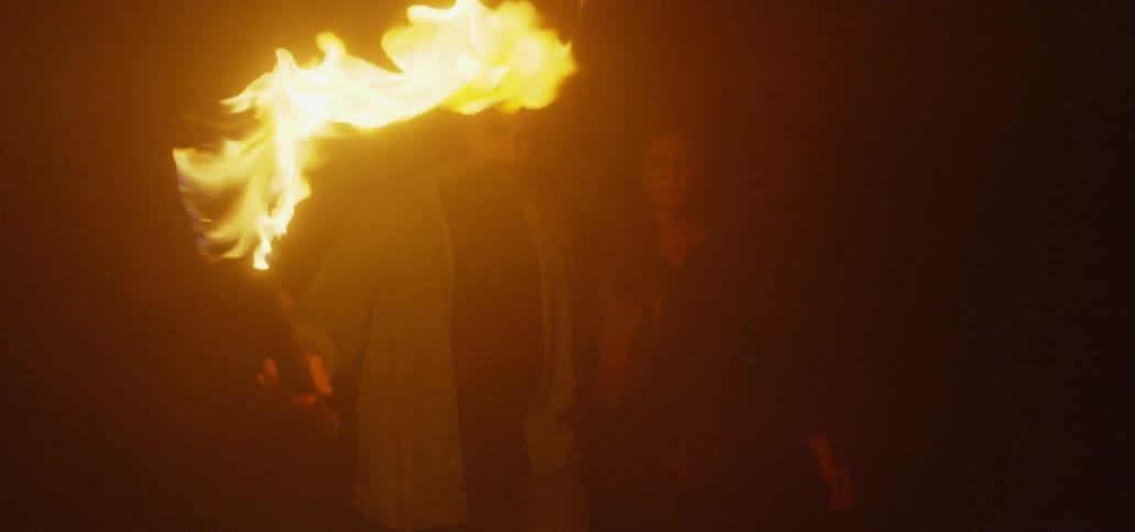 Man and woman carrying a torch walk in the dark at night