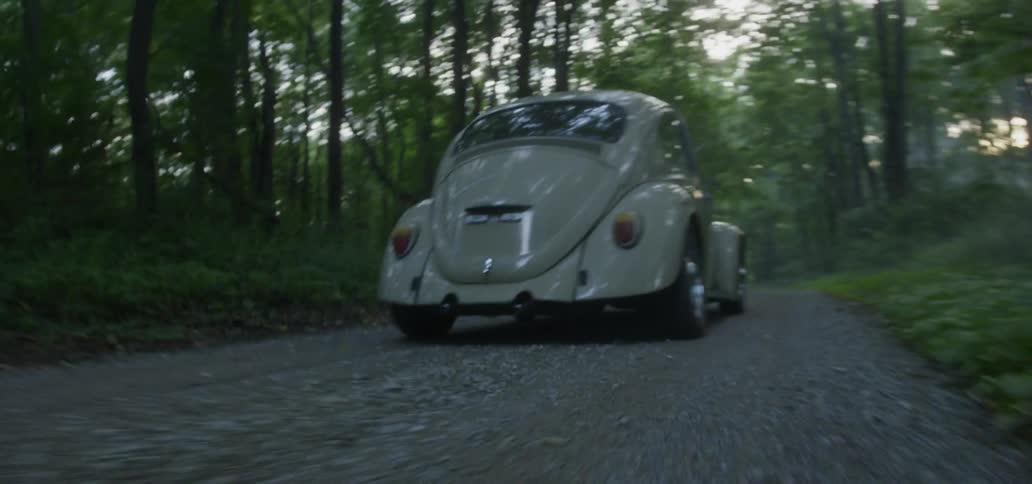 A Volkswagen car driving down a dirt road in the woods
