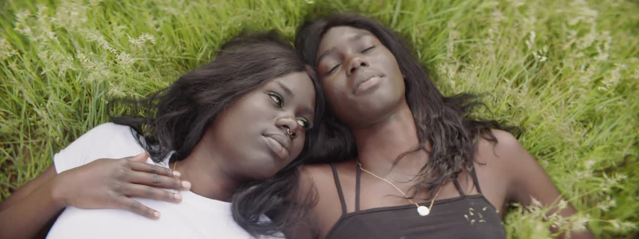 Two girls lay back on grass