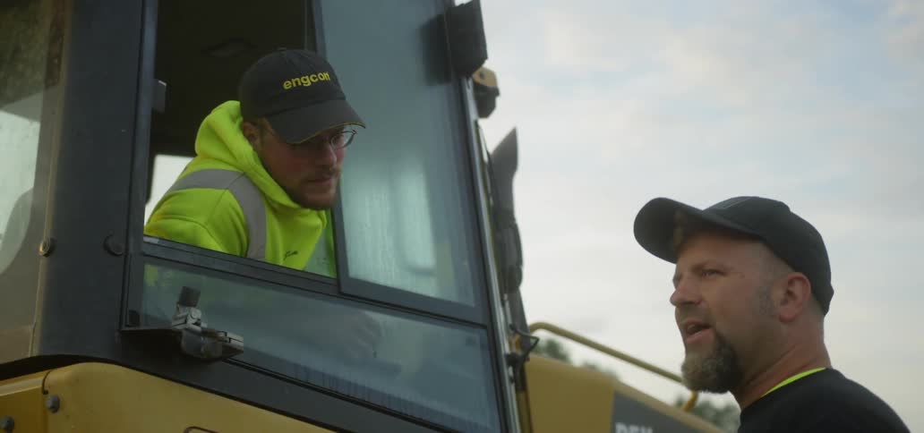 A man leans out of his truck talking with someone