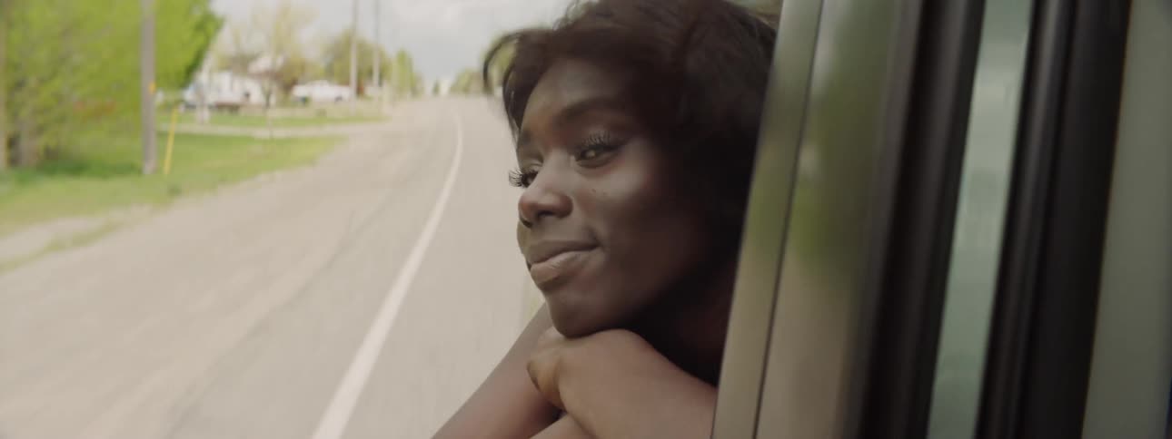 A woman hangs her head out of the passenger side window