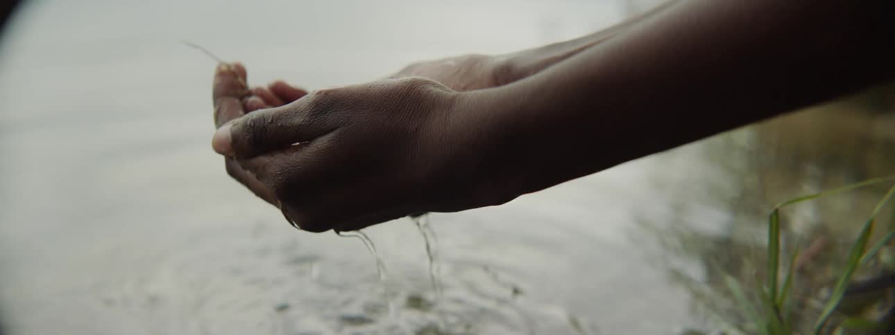 A person cups their hands in water and brings them up