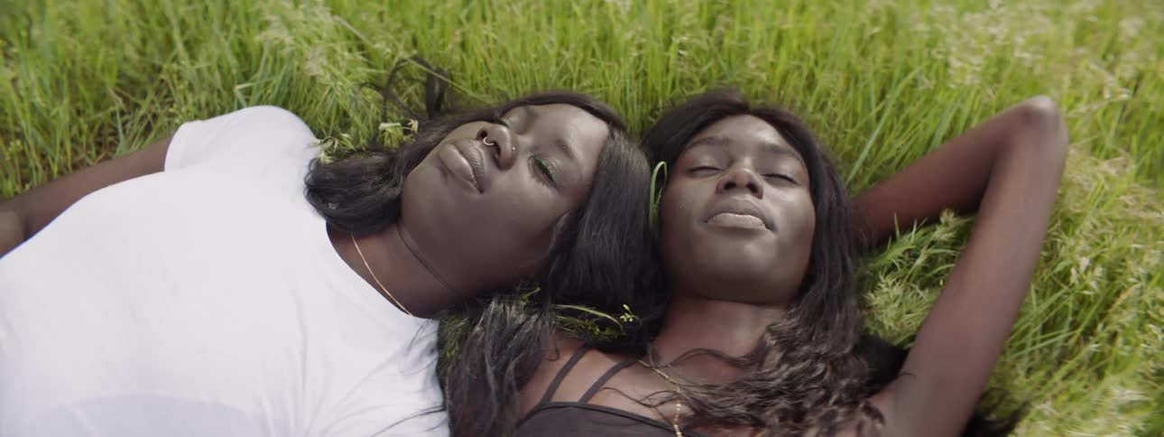 Two women are laying in the grass outdoors