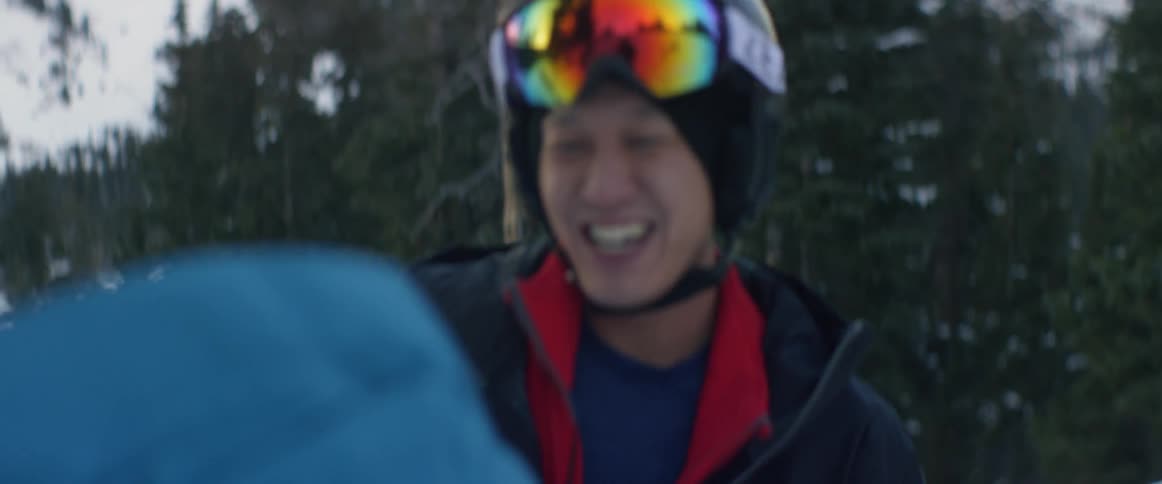 Two young men fist bumping and smiling on a snowy mountainside