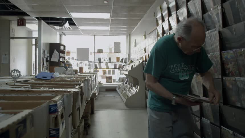 Man puts magazines on a shelf in an empty store