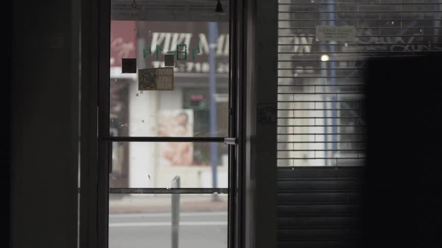 A view looking from inside of a building out to the street as someone walks past the doorway