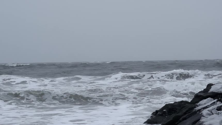 Waves crashing and foaming under a cloudy sky