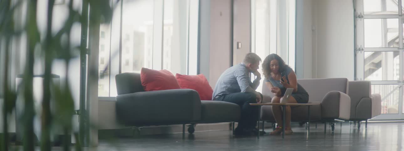 A man and woman talk while looking at a laptop