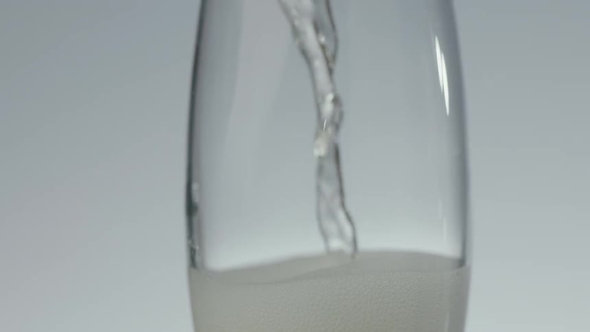 Clear liquid pours into a champagne glass
