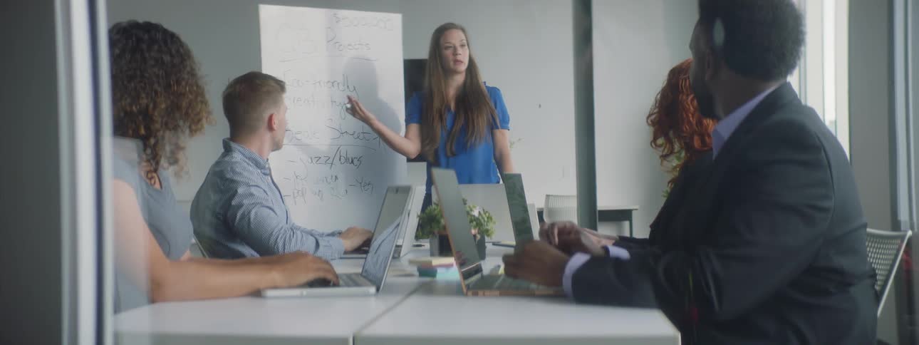 A woman is talking to a group of people and writing