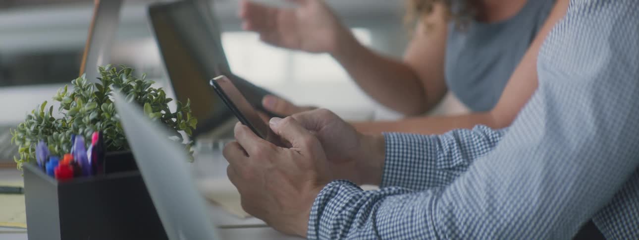 A woman talking to a man as they both look at their phones