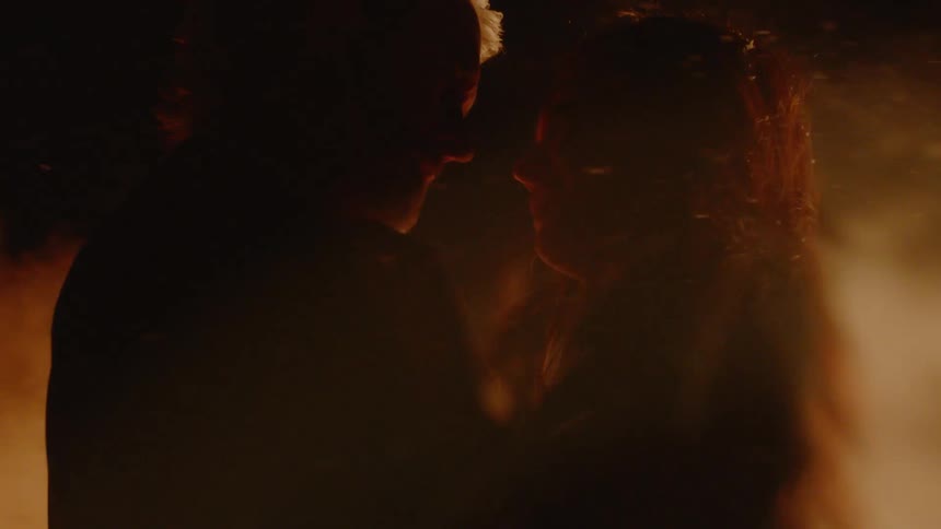 Man and woman holding each other in the dark with smoke blowing past them