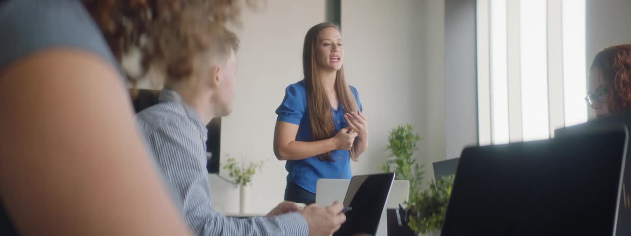 A woman is talking in front of a table of people