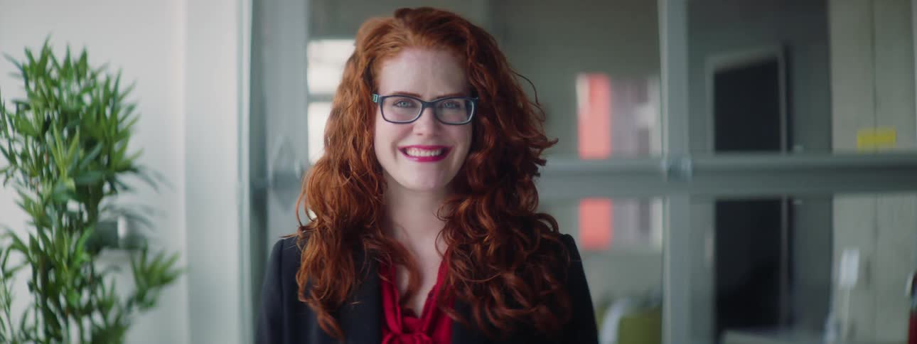 A woman wearing glasses smiling in an office