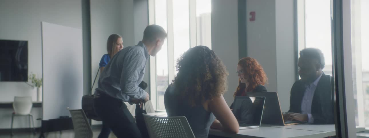 A group of people sit at a table with the laptops