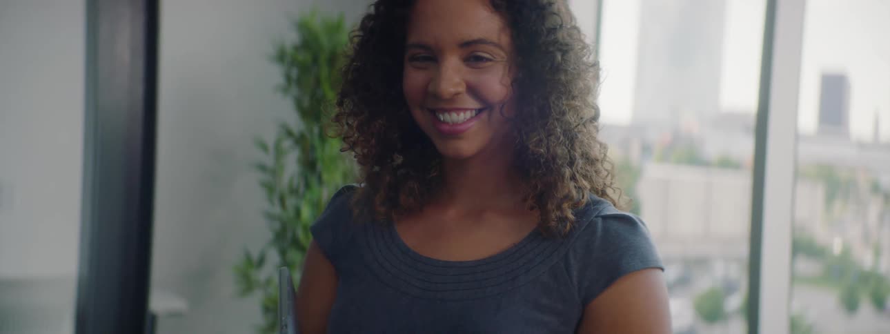 A woman smiles while standing next to a window