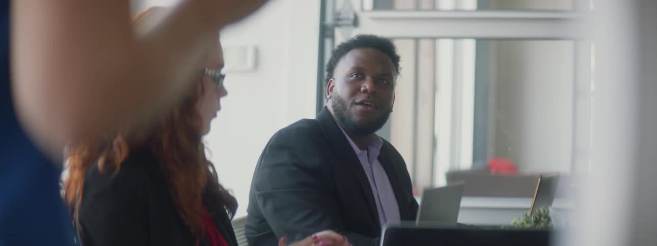 People converse around a table in a meeting