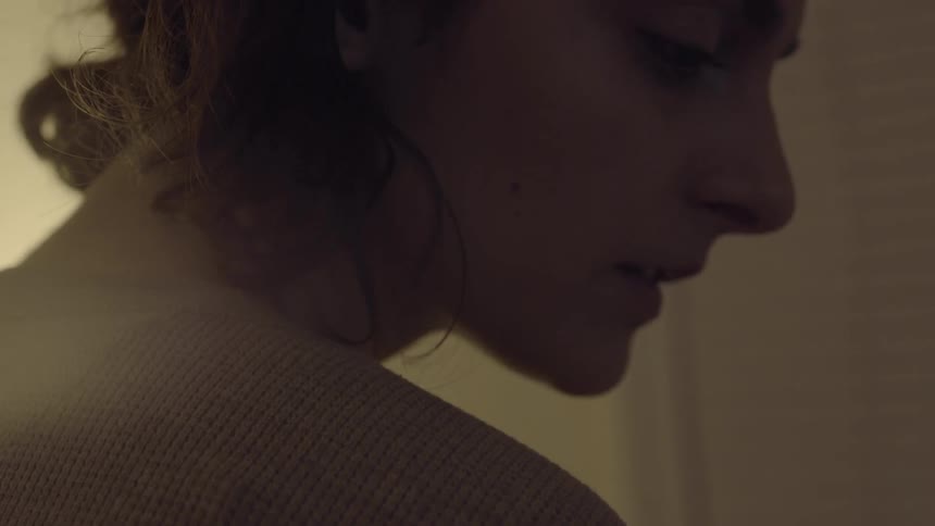 A young woman with brown hair turns her head to the side