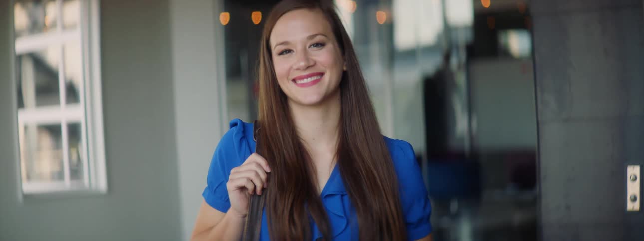 A woman is carrying a briefcase and smiling
