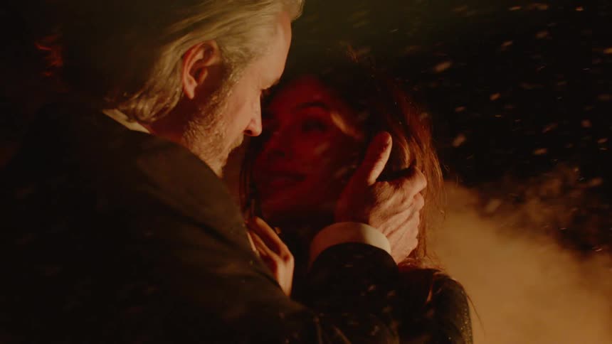 Man touches woman's hair and they kiss surrounded by smoke