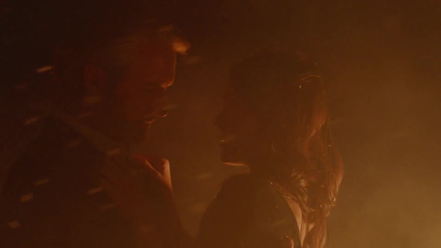 Man touches woman's hair and they hug outside by fire and smoke