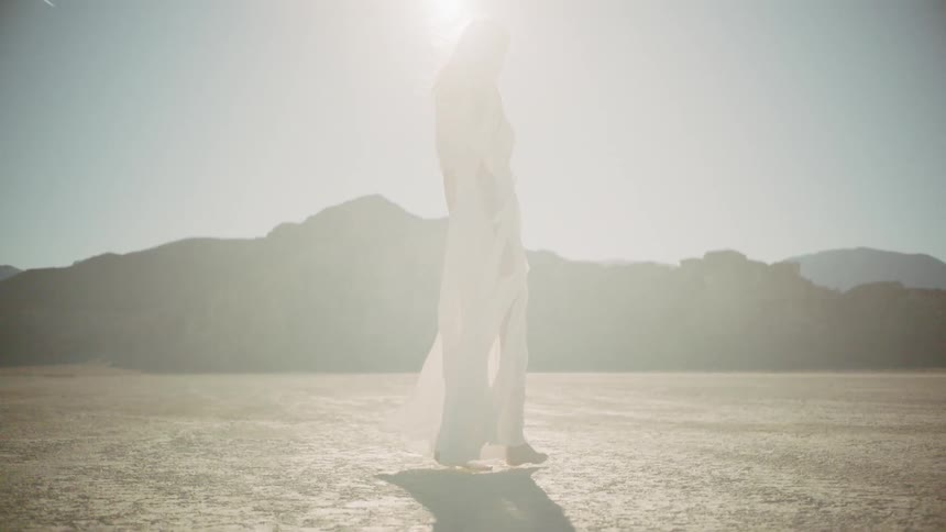 A woman in a white dress standing in a sunny dry desert