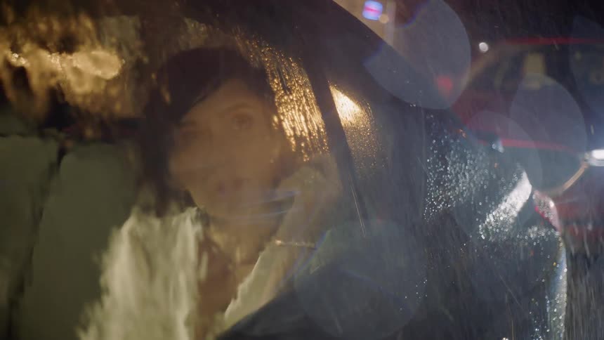 A woman sits in a car during a rainstorm