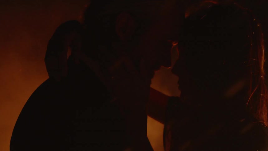 Man and woman are embracing next to bonfire at night