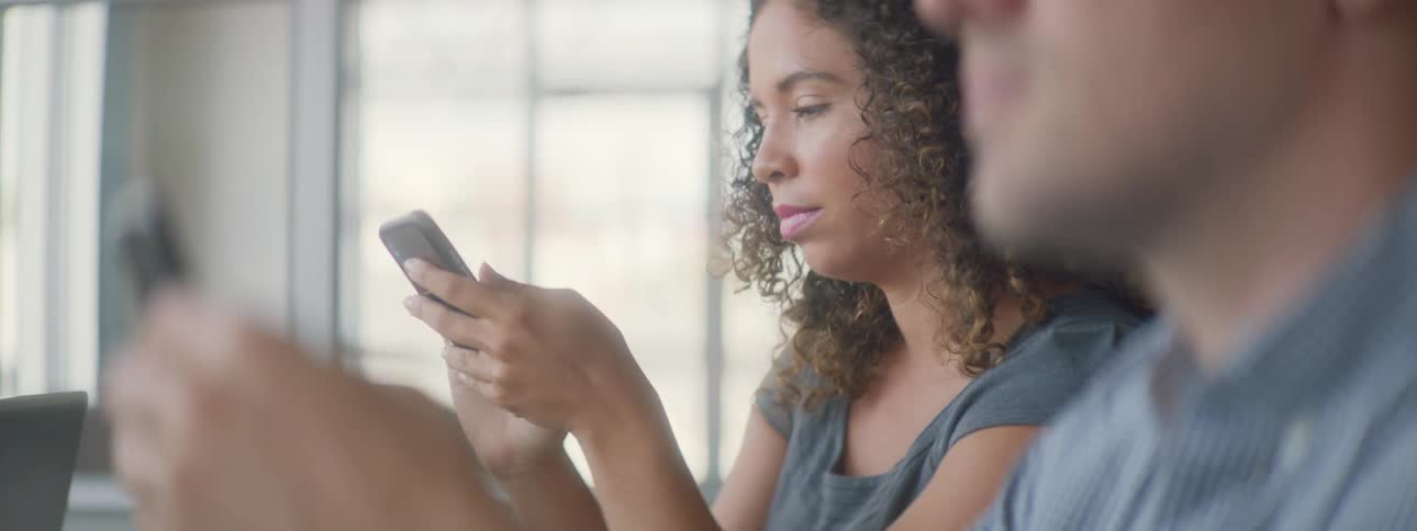 A woman is on her phone while sitting down