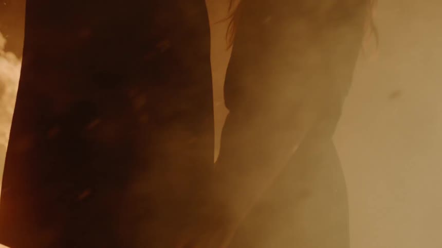 A woman and man are outside by a fire