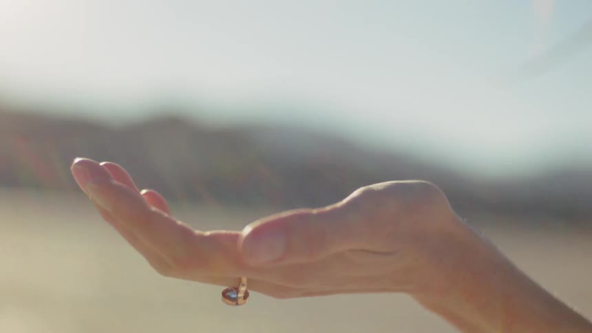 A woman with a ring on opening her hand in the sunlight