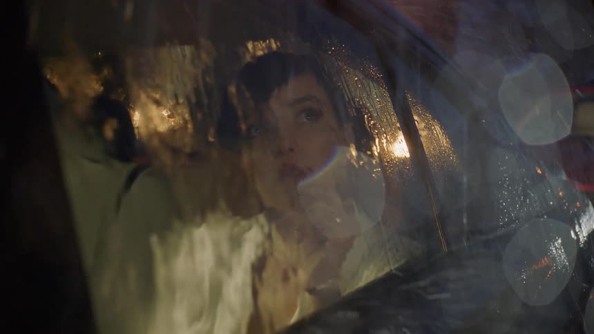 Woman is sitting in car and watching rain storm outside