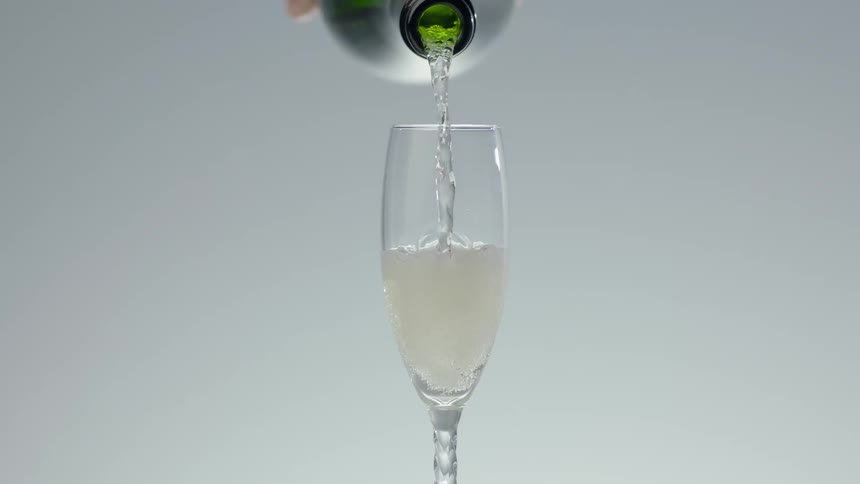 A bottle of champagne pouring in a flute