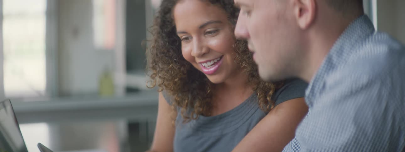 A man and a woman talking while looking at their phones