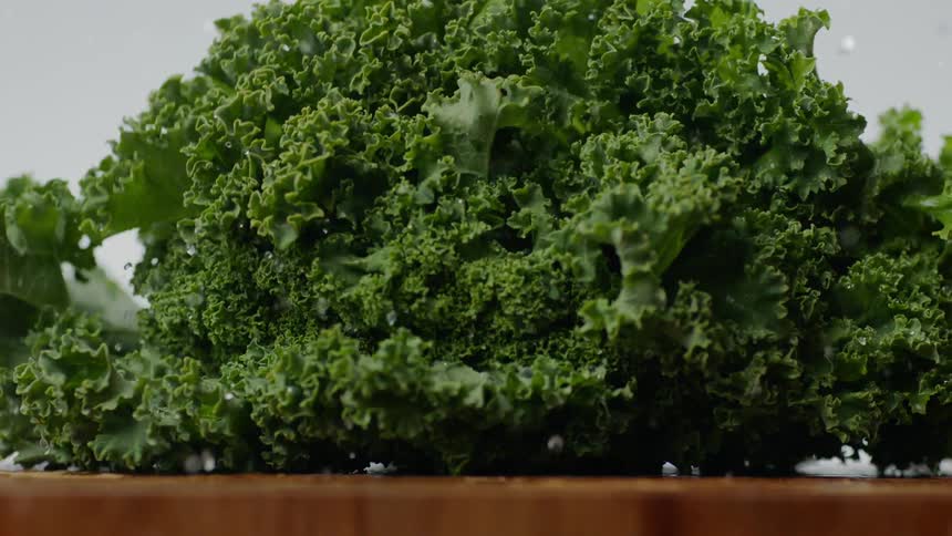 Wet kale leaves drop onto table