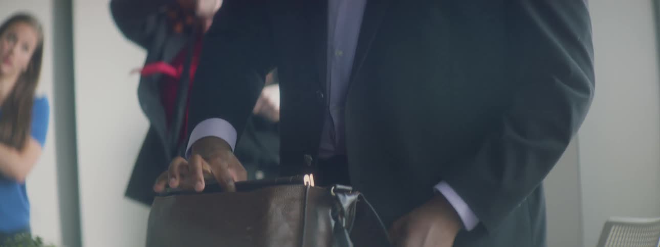 Employees pack of their belongings at the end of a work meeting