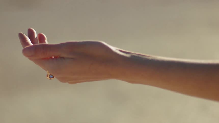 A woman with a ring on her finger holding out her hand in the sunlight